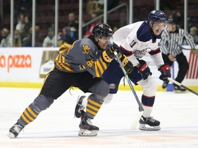Sarnia Sting's Nolan Burke, left, and Saginaw Spirit's Olivier Savard chase the puck in the first period at Progressive Auto Sales Arena in Sarnia, Ont., on Friday, Nov. 5, 2021. Mark Malone/Chatham Daily News/Postmedia Network