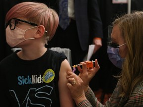 A child gets vaccinated for COVID-19 at the Metro Toronto Convention Centre, in Toronto, Tuesday, Nov. 23, 2021.