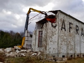 A Priestly Demolition Inc. high-reach excavator pulls off a piece of orange roofing during demolition of the old warehouse at the Caframo manufacturing site overlooking Colpoys Bay in Wiarton, Ont. on Thursday, Nov. 18, 2021. (Scott Dunn/The Sun Times/Postmedia Network)