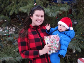 Kaija Saunanen, along with her 10-month-old baby Reija, holding up one of the goodie bags in front of the Main St. Christmas tree.