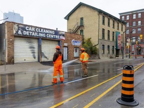 Workers from Enwave wash the mud off of York Street after a rough asphalt patch was installed in front of Finest Auto Detailing in downtown London. An underground steam pipe ruptured Friday afternoon, blowing a large hole in the sidewalk and sending plumes of steam in the the air. No one was injured. Photograph taken on Sunday Oct. 31, 2021. (Mike Hensen/The London Free Press)