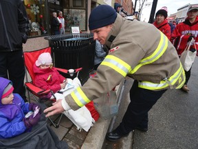Owen Sound Fire Dept. firefighter Paul Materiuk hands out candy to Julia Rabidoux, 4, left, and Adalyn Fisher, 4, during the 71st annual Kiwanis Club of Owen Sound Santa Claus Parade on Saturday, November 19, 2016 in Owen Sound, Ont. James Masters/The Owen Sound Sun Times/Postmedia Network