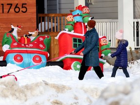 Two people and a small dog walk past a colourful holiday display in Winnipegon Saturday Nov. 20. 2021.