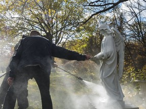 Campbell Monument crew members power-wash a plastic angel stature in Mount Evergreen Cemetery where, so far, a total of 46 headstones have been spray painted with graffiti. Tuesday in Quinte West, Ontario. ALEX FILIPE