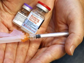 A public health nurse holds vials of the Pfizer-BioNTech and Moderna COVID-19 vaccines and a syringe at Hastings Prince Edward Public Health in Belleville.