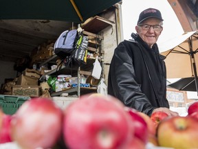 Clifford Foster from Fosterholm Farms poses alongside some of his farm's apples Saturday morning at the Belleville Farmers Market square. ALEX FILIPE