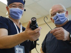 Drs. Meng Guan, left, and Edward Woods hold a ureterscope and its flexible tip. Multiple scopes are needed to ensure a maximum number of patients can be seen in a given day.