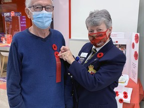 Chrystal Petit-Pas, secretary for District B, of the Royal Canadian Legion, pins a poppy on volunteer Cyril Irving at the Zehrs grocery store on King George Road.