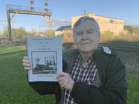 Robert Hasler holds a copy of The Changing Times, volume 2 of Paris Junction - Paris Station (1900-1960) by the railroad tracks in his Prais neighbourhood.  A book launch is scheduled for Nov. 21, 2 p.m. to 4 p.m,. at the Paris Museum.