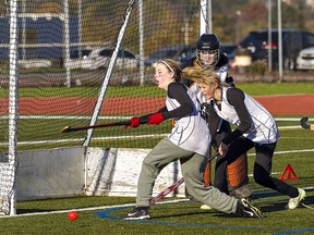 Victoria Cheney (centre) and Kieya Gregory of the Assumption Lions try to regain control of the ball that rolled wide of the Cayuga Warriors net and goaltender Taryn Cooper during a semi-final girls field hockey match on Wednesday  at Kiwanis Field in Brantford.