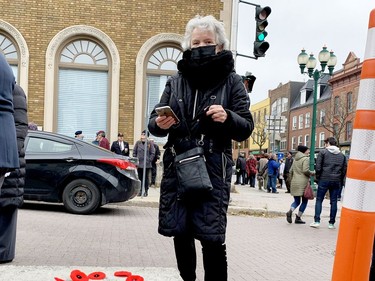 Nicole Levesque, of Brockville, takes a picture after arranging poppies in a heart shape following Brockville's Remembrance Day ceremony. (RONALD ZAJAC/The Recorder and Times)