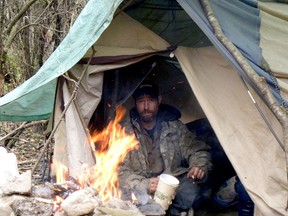 Joey Sullivan, who has been homeless for nearly three months, warms himself by a fire in a homeless encampment in Brockville on Monday afternoon. (RONALD ZAJAC/The Recorder and Times)
