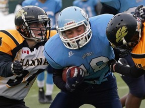 Millwoods Christian Royals quarterback Spencer Gibson is tackled by JC Charyk Hawks Wendel Siewert (left) and Dylan Hann (right) during the Alberta Schools' Athletic Association provincial high school football championship game held at Commonwealth Stadium in Edmonton on Friday November 26, 2021. Royals won the game 60-48. LARRY WONG/POSTMEDIA