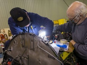 Canadian Harvard Aircraft Association volunteers Wayne Buchanan and William Wright get in close Tuesday to label wires before they strip down the cockpit instrumentation on a torn-down Second World War Harvard they are rebuilding at association headquarters at Tillsonburg airport. (Mike Hensen/Postmedia)