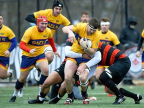 Queen's Gaels' Ruairidh MacPhail runs with the ball as Malcolm Shields, left, and Noah King help against the Guelph Gryphons in the bronze medal game at the Canadian University Men's Rugby Championship on Sunday, Nov. 28, 2021. Queen's won the game, 13-5.