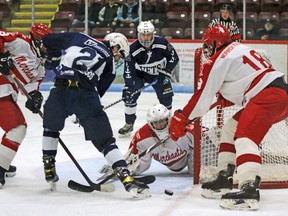 Woodstock's Drew Woods looks for a loose puck near Norwich Merchants' goalie Austin Strom Friday night at Southwood Arena.