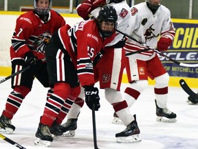 Carter Lewis (7), Sean Chisholm (15) and Patrick Holloway (18) of the Mitchell Hawks battle for the puck against visiting Hanover Barons Oct. 2 at the Mitchell & District Arena. The Barons snapped a 3-3 tie with under four minutes to left to defeat the Hawks in their PJHL home opener, 4-3.