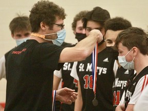 St. Marys DCVI senior boys' volleyball coach Steve Chateauvert hands out gold medals to his players after a five-set win over Goderich in the Huron-Perth single-A championship Tuesday at DCVI.