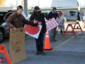 From left, Sean Murphy, Arthur Kicknosway, a man who declined to be identified, and Joyce Ireland protest outside a mobile COVID-19 vaccine clinic on Monday November 1, 2021 in Petrolia, Ont. Terry Bridge/Sarnia Observer/Postmedia Network