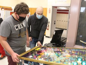 Student Billy Brooks, left, and Mike Primeau from Path of Play try out a pinball machine the non-profit donated to Lambton Central Collegiate and Vocational Institute in Petrolia. The group also donated a board game library and a video game console to create what's being called The Playroom Experiment at the school to serve students with special needs and those struggling with social isolation. (Paul Morden/The Observer)