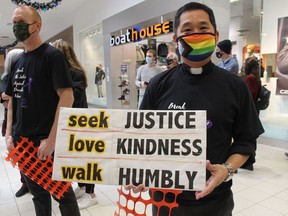 Rev. Kenji Marui of Grace United Church holds a sign Saturday during a Women's Interval Home Walk a Mile fundraiser and awareness event held at Lambton Mall in Sarnia.