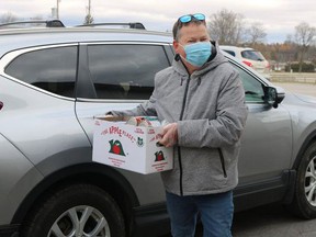 Volunteer Dave Kent takes a donation out of a vehicle during last year's drive-thru food drive held at the Aud at the Simcoe fairgrounds. This year's event runs on Nov. 23.  File photo
