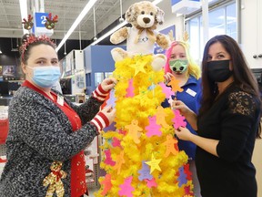 Charli White, left, and Cloe Cardinal, of Toys R Us, and   Lynne Ethier, right, of Our Children, Our Future, decorate a tree with paper ornaments featuring children's names at the launch of the annual Tree of Dreams Toy Drive in Sudbury, Ont. on Friday November 12, 2021. Our Children, Our Future and Toys R Us in Sudbury have partnered up to help ensure that less fortunate children in Greater Sudbury will receive a gift on Christmas Day.  People can support the toy drive by choosing an ornament from the Tree of Dreams, purchase a gift for that child and a Toys R Us associate will place the ornament and the unwrapped gift in a bag. John Lappa/Sudbury Star/Postmedia Network