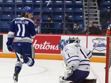 Landon McCallum, left, of the Sudbury Wolves, leaps out of the way of a shot in front of goalie Roman Basran, of the Mississauga Steelheads, during OHL action at the Sudbury Community Arena in Sudbury, Ont. on Friday November 26, 2021. John Lappa/Sudbury Star/Postmedia Network