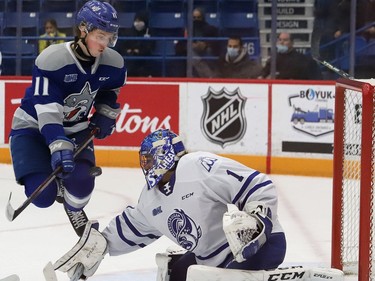 Landon McCallum, left, of the Sudbury Wolves, leaps out of the way of a shot in front of goalie Roman Basran, of the Mississauga Steelheads, during OHL action at the Sudbury Community Arena in Sudbury, Ont. on Friday November 26, 2021. John Lappa/Sudbury Star/Postmedia Network