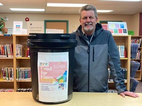 Claude Rocheleau, General Manager of the Food Bank gratefully accepts this pail of non-perishable food items from the Cochrane Public Library. The win-win situation enabled patrons to pay off their fines with food and the Food Bank is now able to distribute that to members of the community in need. Library photo