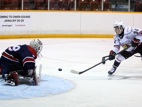 Thomas Chafe lifts the puck by goaltender Andrew Oke to open the scoring while Camaryn Baber gives chase in the first period as the Owen Sound Attack host the Saginaw Spirit inside the Harry Lumley Bayshore Community Centre Saturday, Nov. 20, 2021. Greg Cowan/The Sun Times