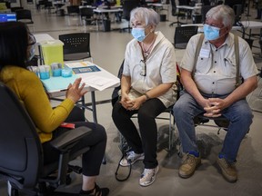 Pamela and Lorry Wilson receive their COVID-19 vaccine from Connie Wong, Registered nurse, at the Telus Convention Centre in Calgary on Tuesday, April 6, 2021. Leah Hennel / ALBERTA HEALTH SERVICES