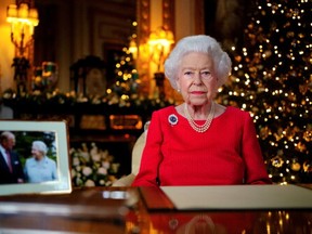 Britain's Queen Elizabeth delivers her annual Christmas broadcast in the White Drawing Room in Windsor Castle next to a photograph of her and the late Duke of Edinburgh. Victoria Jones/Pool via REUTERS/File