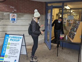 Cheryl Lepelaan picks up some books she ordered online from librarian assistant Isaac Demeester after the Stratford Public Library announced this week it was moving back to curbside-pickup only due to COVID-19 related staffing shortages. (Galen Simmons/The Beacon Herald)