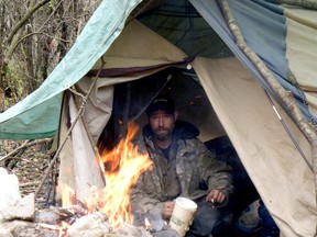 Joey Sullivan, who had been homeless for nearly three months, warms himself by a fire in a homeless encampment in Brockville on Nov. 15.  (RONALD ZAJAC/The Recorder and Times)