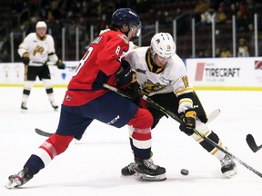 Sarnia Sting's Angus MacDonell, right, battles Windsor Spitfires' Nathan Ribau for the puck in the first period at Progressive Auto Sales Arena in Sarnia, Ont., on Friday, Dec. 3, 2021. Mark Malone/Chatham Daily News/Postmedia Network