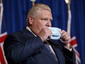 Ontario Premier Doug Ford puts his mask back on after speaking during a press conference at Queen's Park in Toronto, Wednesday, Dec. 15, 2021.