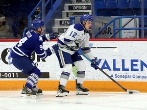 Sudbury Wolves forward Ryan Smith (12) handles the puck while under pressure from Mississauga Steelheads forward Aidan Prueter (94) during first-period OHL action at Sudbury Community Arena in Sudbury, Ontario on Friday, December 31, 2021.