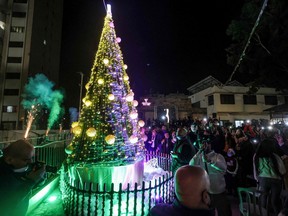 Palestinian Christians, also accompanied by Muslims, light up the Christmas tree in the courtyard of the YMCA Gaza in Gaza City on December 10, 2021. (Photo by MOHAMMED ABED / AFP)