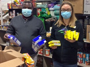 Gleaners Food Bank volunteer Mark Edehwosa of Loyalist College and employee Tara Ryan hold food in the warehouse. Gleaners is in urgent need of volunteers and always needs donations of food and money.