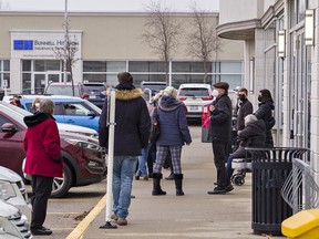 People wait outside a Brant County Health Unit clinic on Friday morning to receive their third dose booster shot.