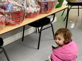 One-year old Rosie Norton helps carry a gift basket created for people in Brockville struggling with homelessness. (SUBMITTED PHOTO)