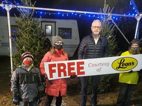 Ken Edwards, owner of Leon's Furniture in Chatham, second from right, holds up a sign for free Christmas trees with Grayson, Brenna and Calvin from the Chatham 19th Scouts troop. Leon's buys up the remaining trees from the Scout troop's fundraiser every year and has them offered for free to those in need.