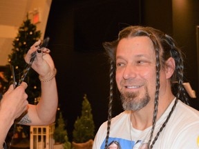 Paul Lafleche peeking at the first braid of his hair that was cut and will be donated to Angel Hair for Kids on Sunday December 19, 2021 in Cornwall, Ont. Shawna O'Neill/Cornwall Standard-Freeholder/Postmedia Network