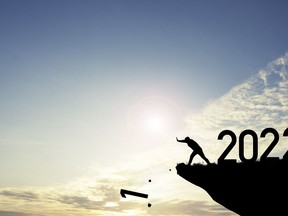 Man push number one down the cliff where has the number 2022 with blue sky and sunrise. It is symbol of starting and welcome happy new year 2022.