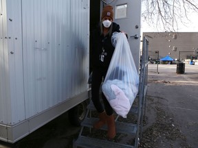Amanda Rogers, manager of harm reduction services at the Integrated Care Hub, removes linens from one of the trailers used by homeless people to isolate after positive COVID-19 results on Tuesday.