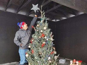 Beaverhouse First Nation Chief Wayne Wabie places a star on the top of a Christmas tree what was decorated by local First Nation Elders.