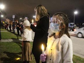 Maren Davidson holds a candle while singing last year outside the Village on the St. Clair in Sarnia as part of The Christmas Ribbon, a project of the Nightingale Chorus. The carolling project is returning this year.