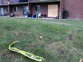 A piece of yellow emergency tape lies on the grass near a boarded-up unit at a Finch Drive apartment building on Wednesday, Dec. 15, 2021 in Sarnia, Ont. (Terry Bridge/Sarnia Observer)