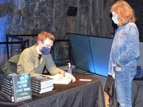 Adam Shoalts signs a copy of his book Whisper On The Night Wind for Linda Weichel of Toronto following a presentation last week at Science North. Jim Moodie/Sudbury Star